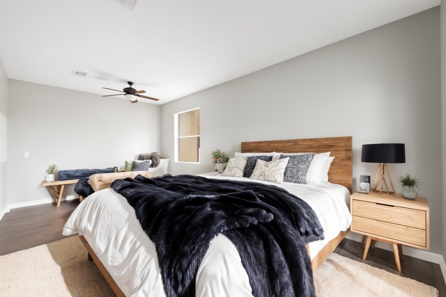 The same bedroom virtually staged with a large bed and headboard, bedside tables, lamps and a rug.
