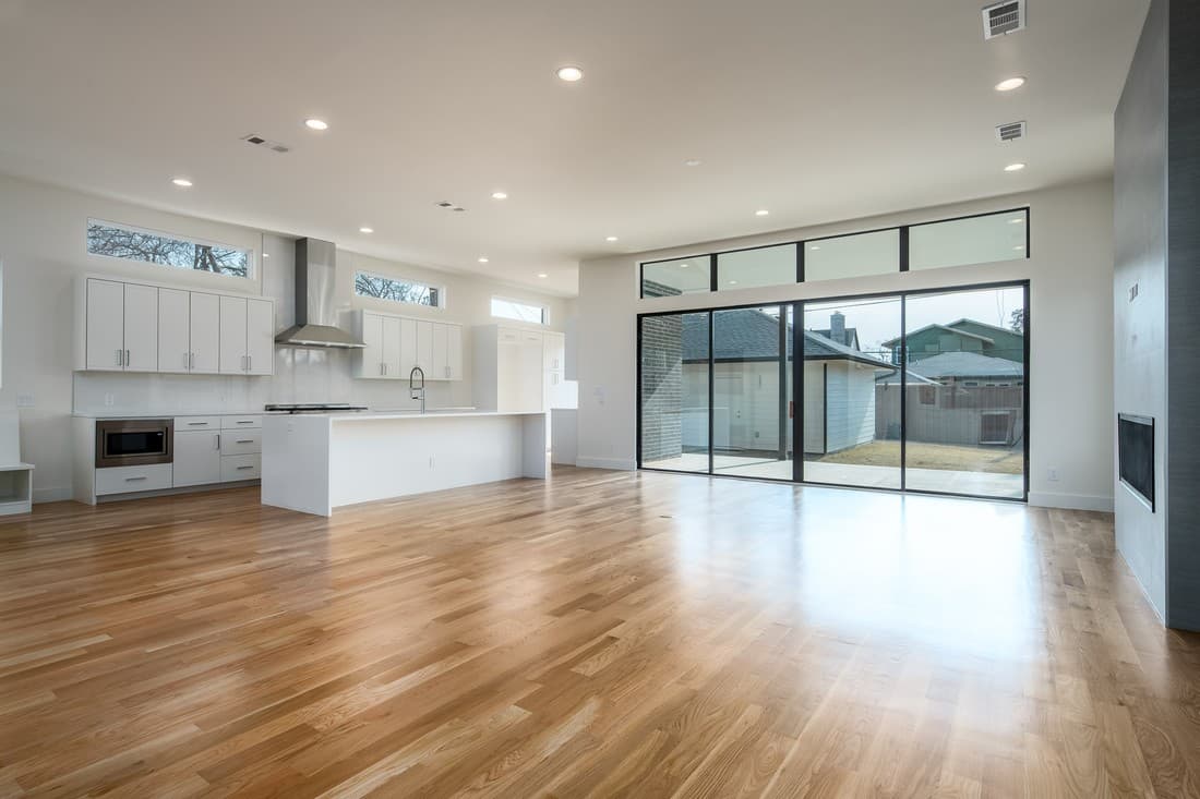 Empty open-plan living and dining area with a kitchen island on the left and sliding doors to a patio.